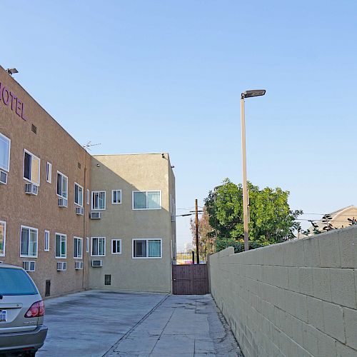 The image shows a car parked in an alley next to a beige building labeled 