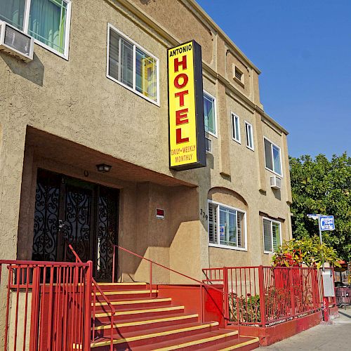 The image shows a small hotel with a red sign reading 